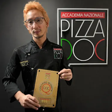 Dhanat, a certified Neapolitan Master Instructor Boss showing Pizza DOC Certificate